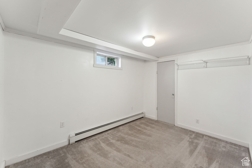 Basement featuring a baseboard heating unit and light carpet