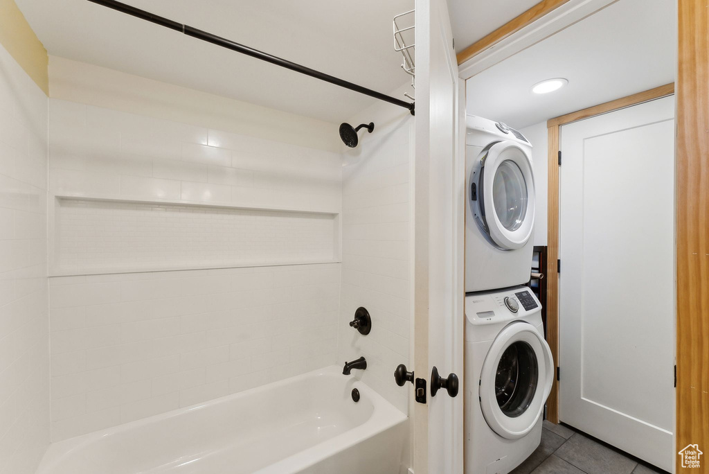 Laundry room with stacked washer / dryer and dark tile patterned flooring