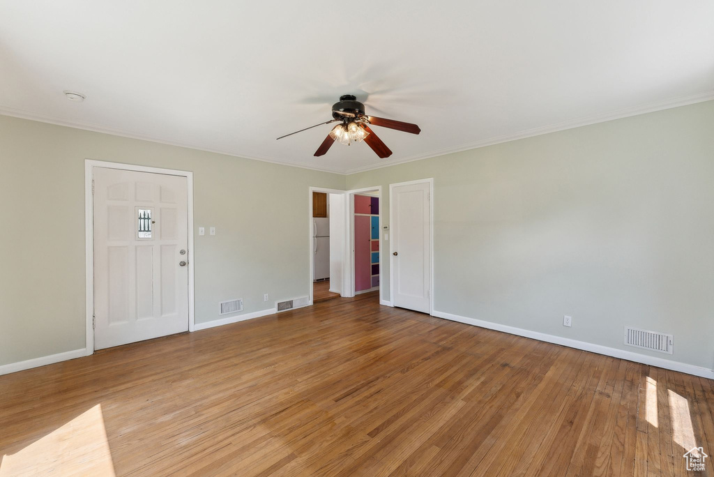 Spare room with a ceiling fan, light wood-style floors, baseboards, and crown molding