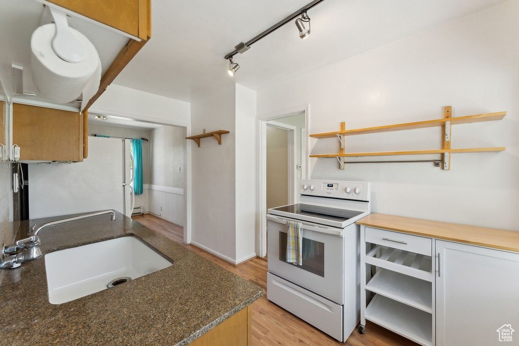 Kitchen featuring open shelves, white appliances, a sink, and light wood finished floors