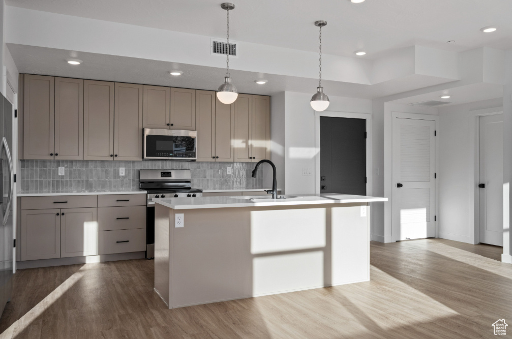 Kitchen with visible vents, wood finished floors, stainless steel appliances, tasteful backsplash, and gray cabinets