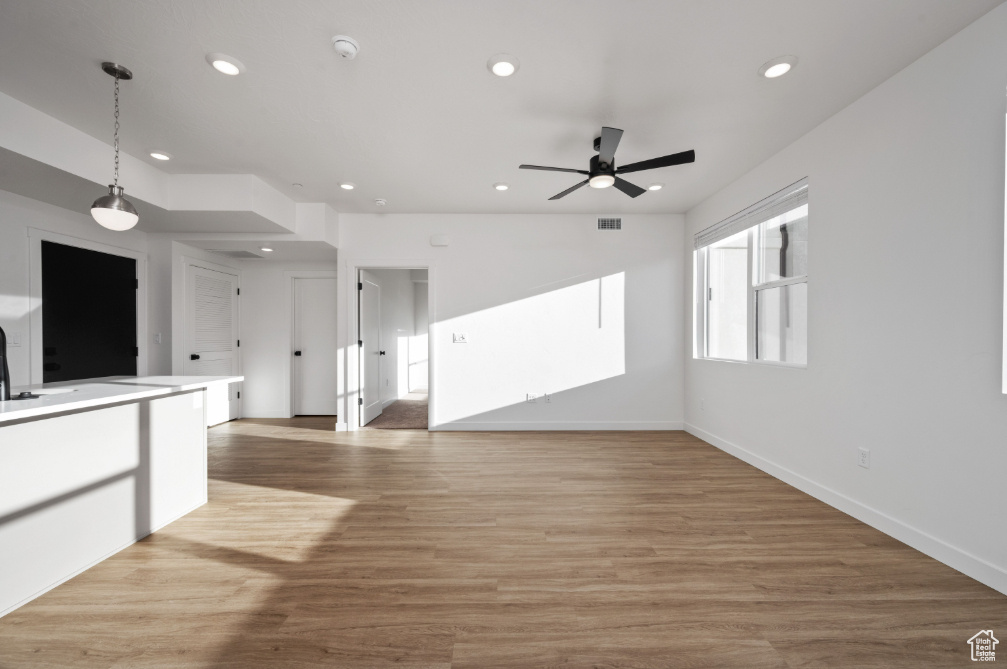 Unfurnished living room with light wood-style floors, baseboards, a ceiling fan, and recessed lighting