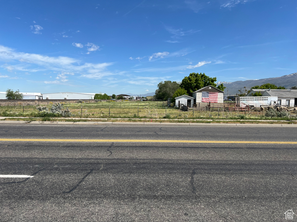 View of asphalt street with curbs, a mountain view, and sidewalks