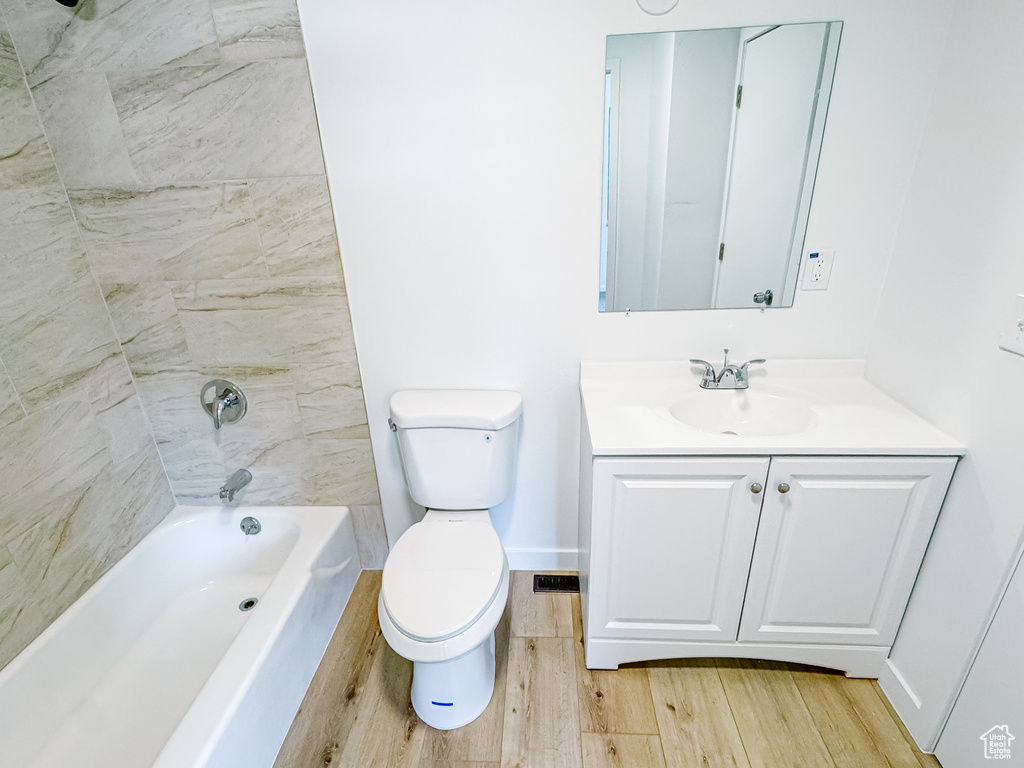 Bathroom featuring wood finished floors, toilet, vanity, and shower / bath combination