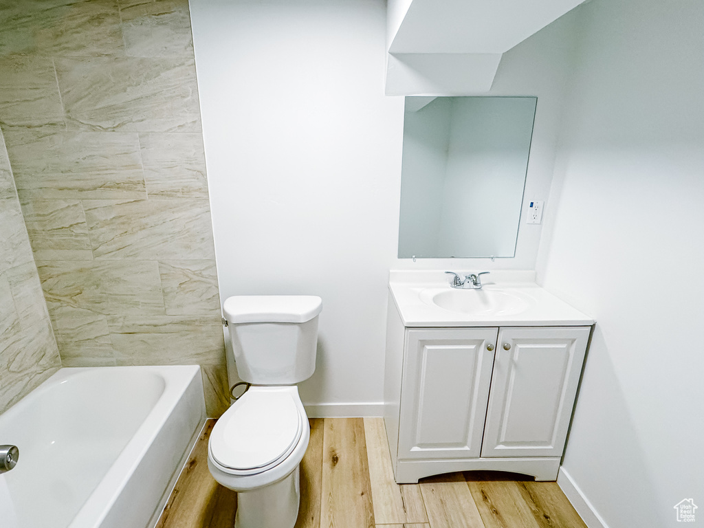 Full bath featuring wood finished floors, toilet, vanity, and baseboards