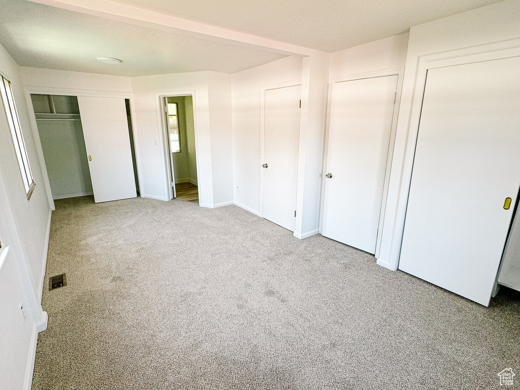 Unfurnished bedroom with carpet floors and two closets