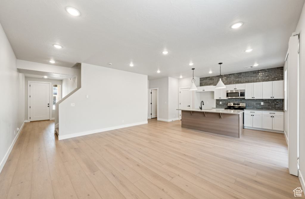 Kitchen featuring stainless steel appliances, open floor plan, recessed lighting, white cabinetry, and baseboards