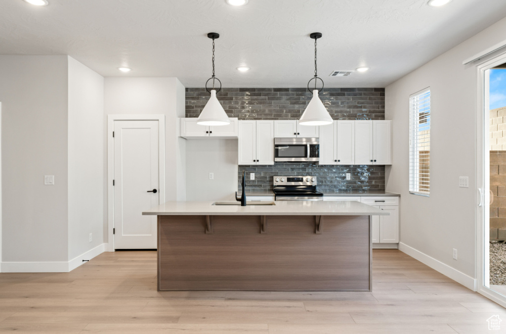 Kitchen featuring stainless steel appliances, tasteful backsplash, a sink, white cabinetry, and recessed lighting