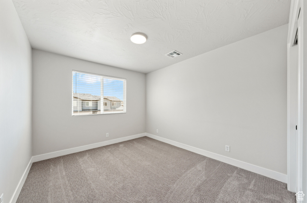 Spare room with carpet floors, baseboards, and a textured ceiling