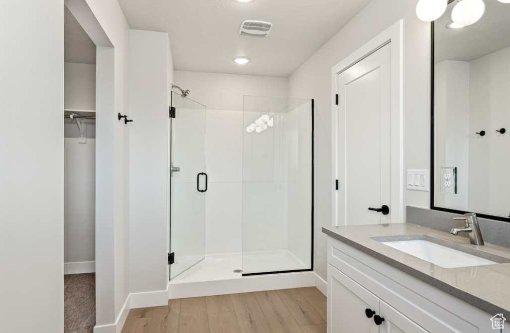 Full bath featuring a stall shower, wood finished floors, vanity, recessed lighting, and baseboards