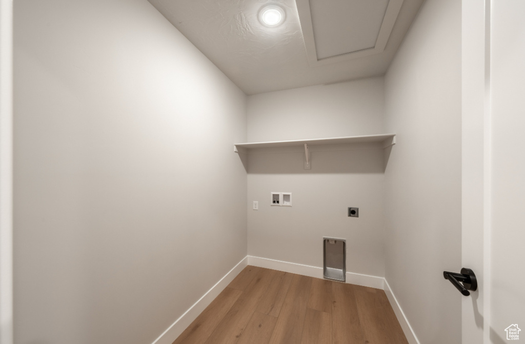 Washroom with hookup for a washing machine, hookup for an electric dryer, baseboards, and light wood-style flooring