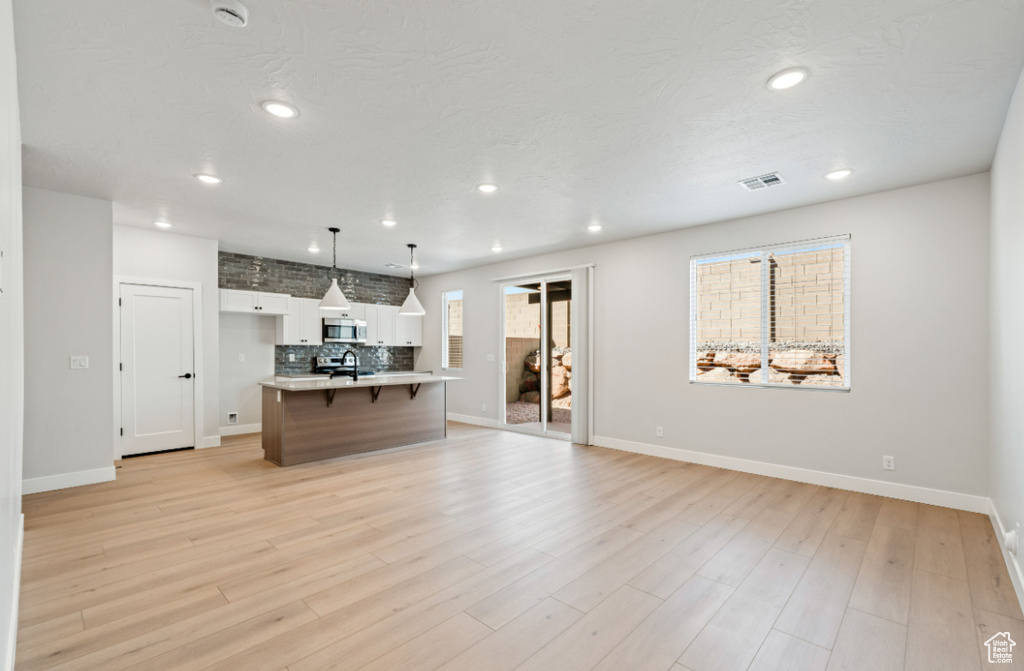 Living room with baseboards, recessed lighting, and light wood finished floors