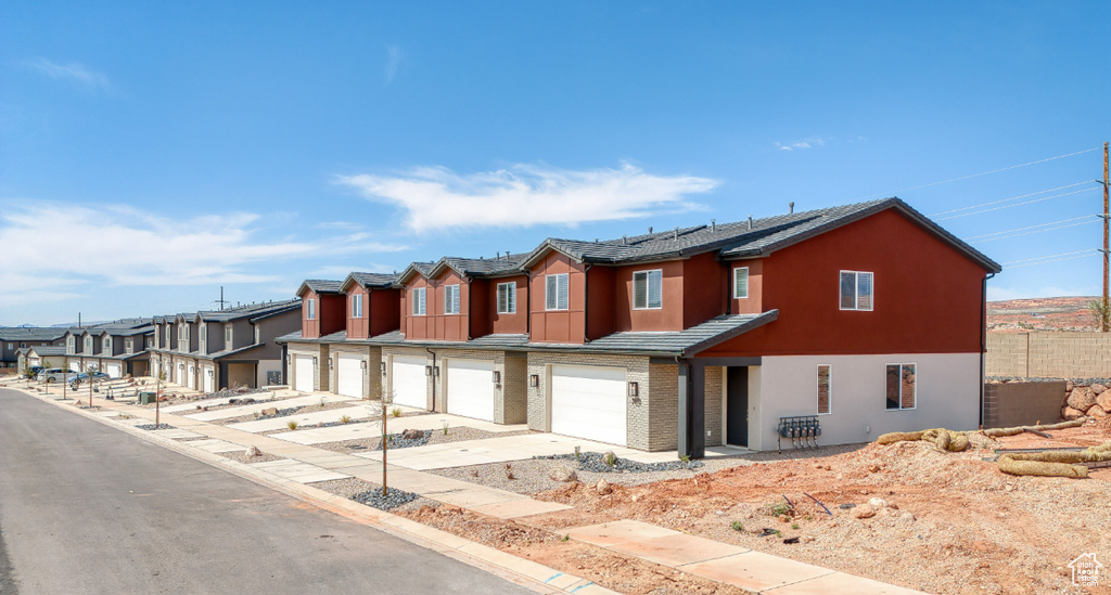 View of property with a residential view, solar panels, an attached garage, fence, and stucco siding