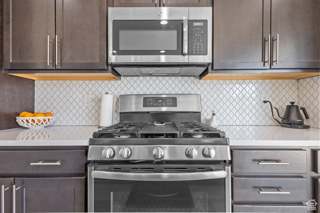 Kitchen featuring stainless steel appliances, dark brown cabinets, light countertops, and tasteful backsplash