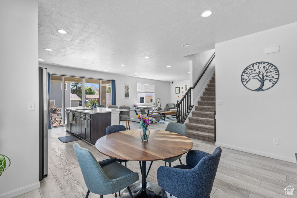 Dining area with stairway, recessed lighting, baseboards, light wood-style floors, and a textured ceiling