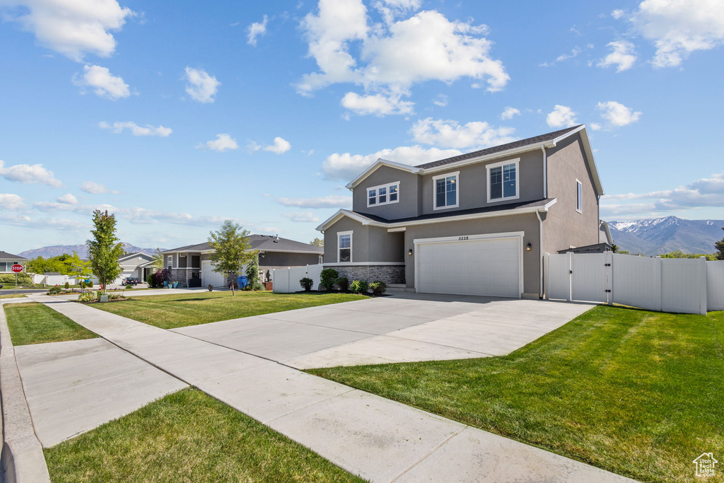 Traditional-style house featuring a gate, an attached garage, driveway, stucco siding, and a mountain view