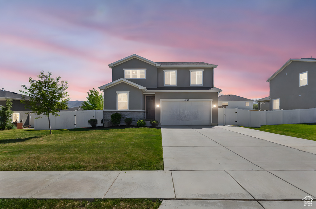 View of front of property featuring stucco siding, concrete driveway, an attached garage, and a gate