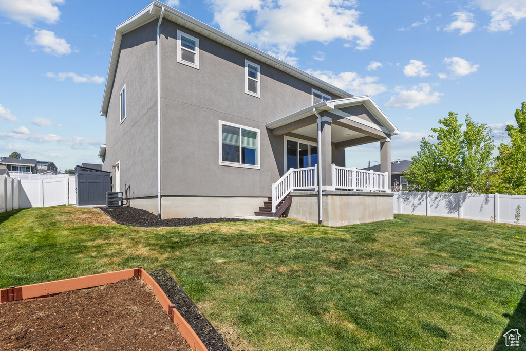 Rear view of property with central AC, stucco siding, and a garden