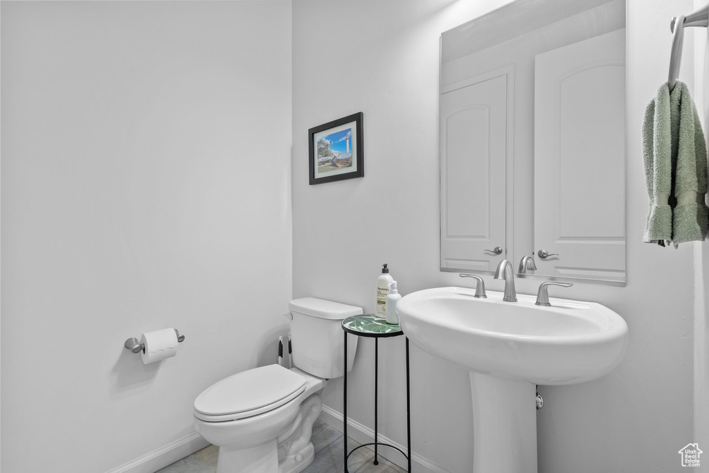 Half bath featuring toilet, baseboards, and a sink