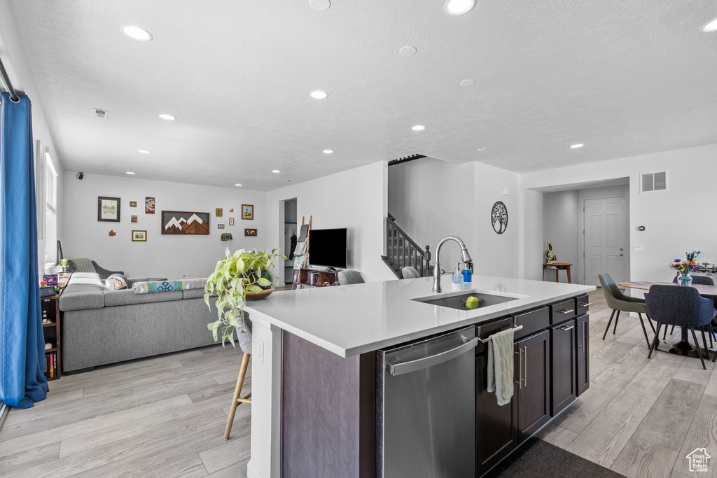 Kitchen with a sink, stainless steel dishwasher, open floor plan, recessed lighting, and light countertops