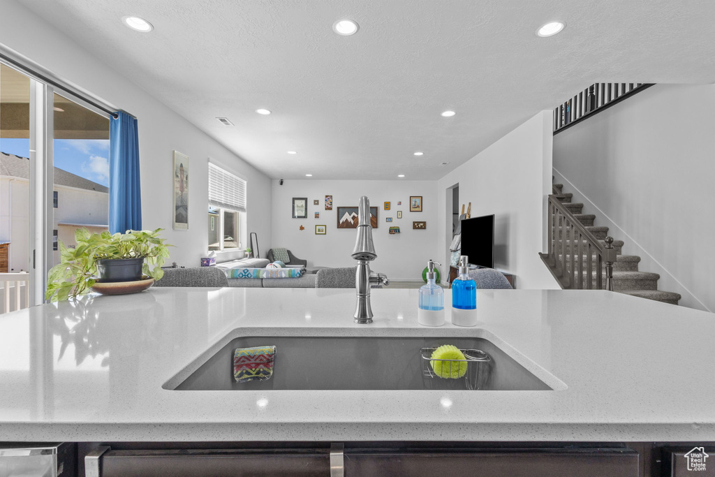 Kitchen featuring a sink, open floor plan, recessed lighting, and light stone countertops