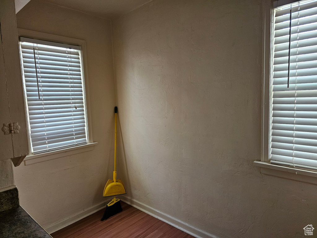 Spare room featuring wood finished floors, baseboards, and plenty of natural light