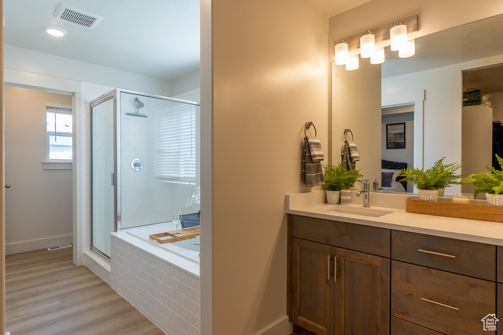 Full bath with a stall shower, vanity, wood finished floors, and a garden tub