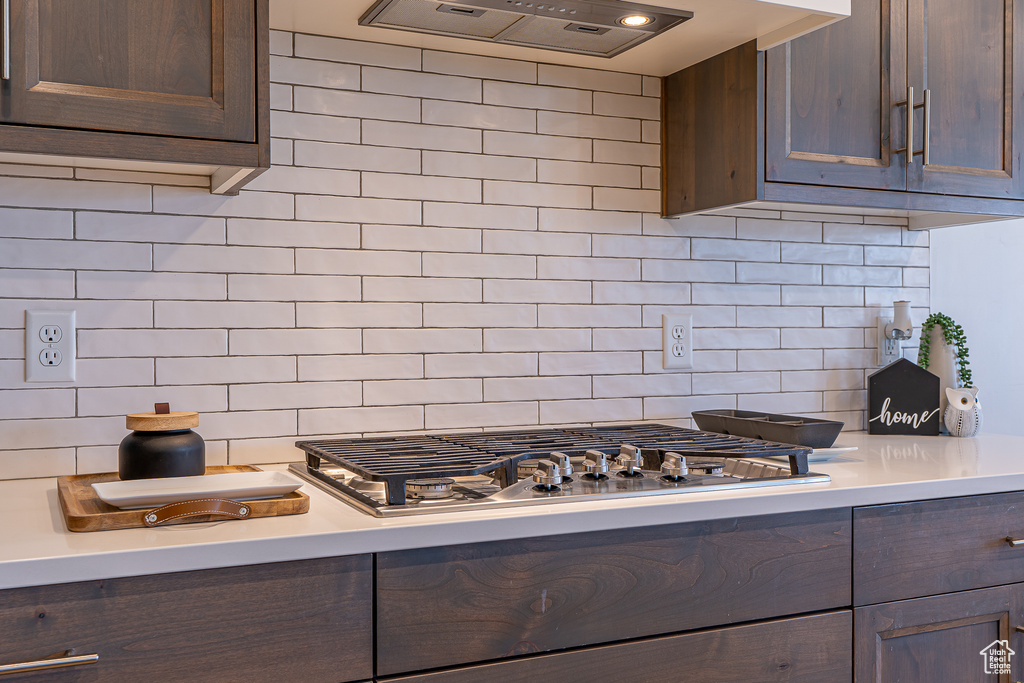 Kitchen with light countertops, custom range hood, tasteful backsplash, and dark brown cabinetry