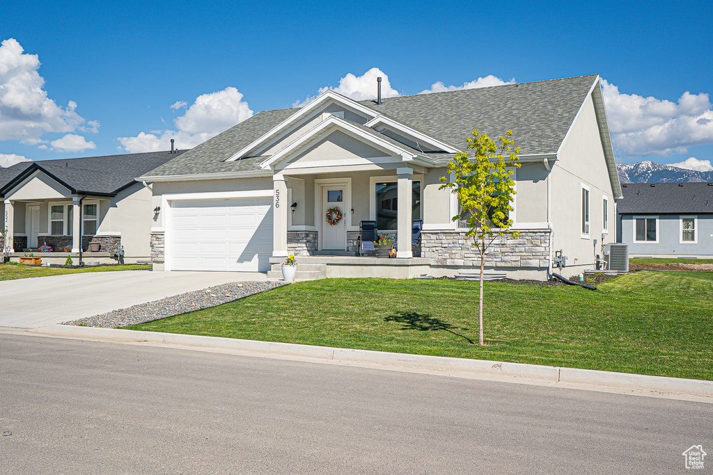 View of front of property with covered porch, stucco siding, central air condition unit, a front lawn, and an attached garage