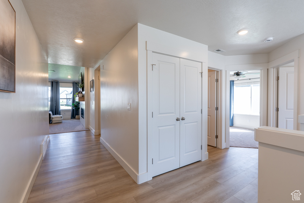 Hallway with light wood-type flooring, baseboards, and recessed lighting