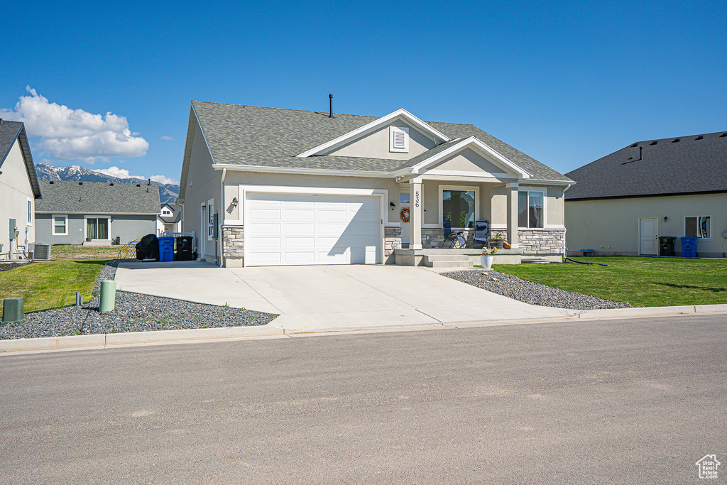 View of front of house featuring stone siding, a garage, stucco siding, and a front lawn