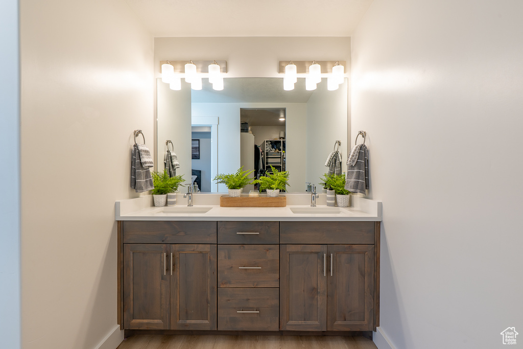 Bathroom featuring double vanity, baseboards, and wood finished floors