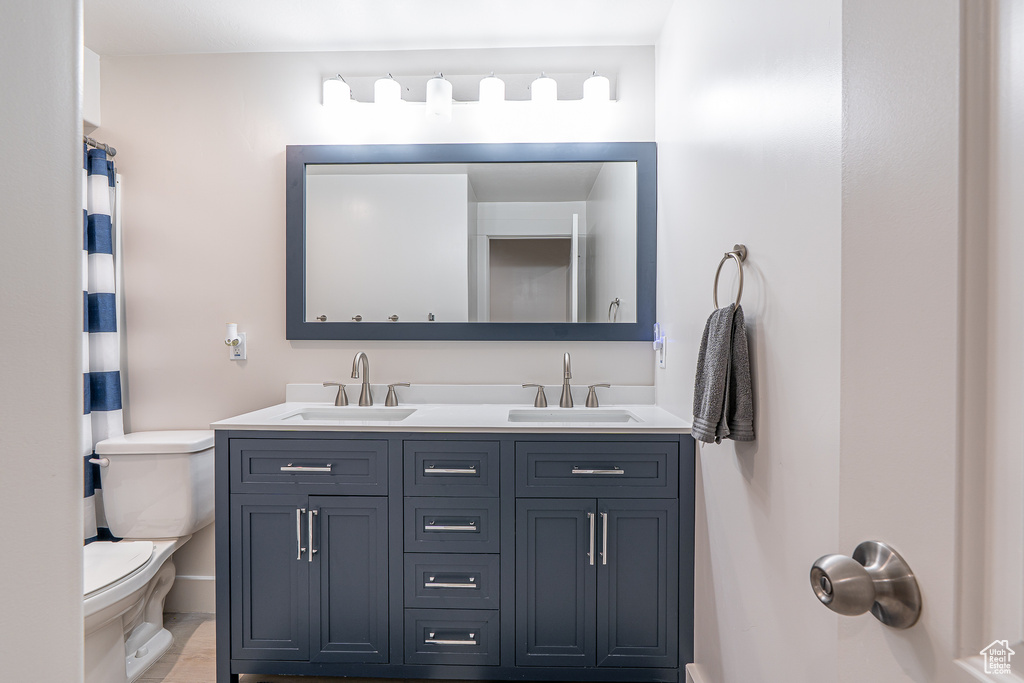 Bathroom with toilet, double vanity, and baseboards