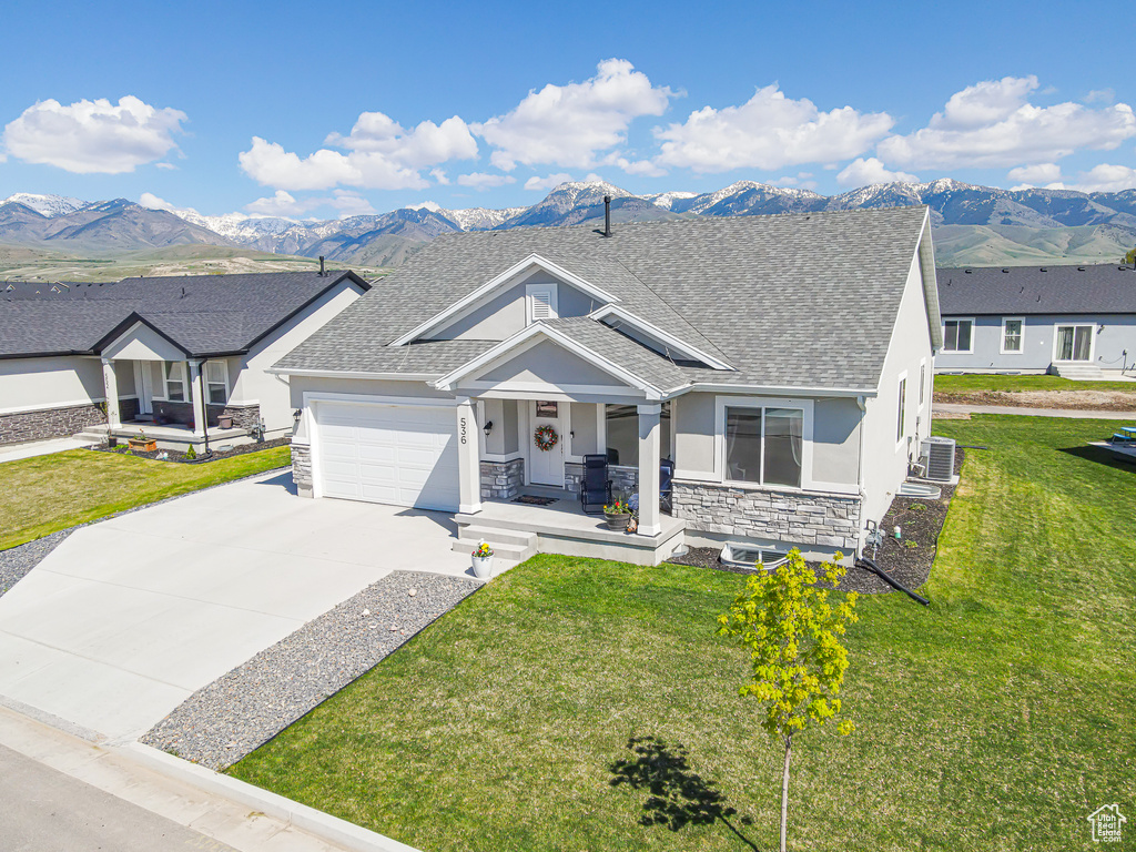 View of front facade with a porch, a mountain view, stucco siding, and stone siding
