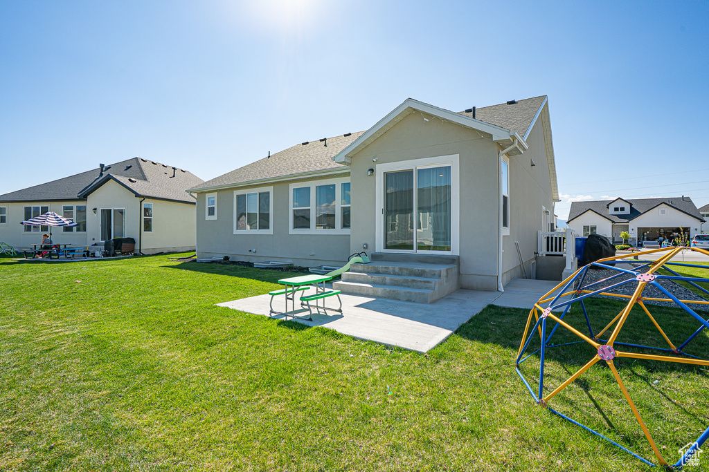 Back of property with a patio, a yard, stucco siding, and roof with shingles