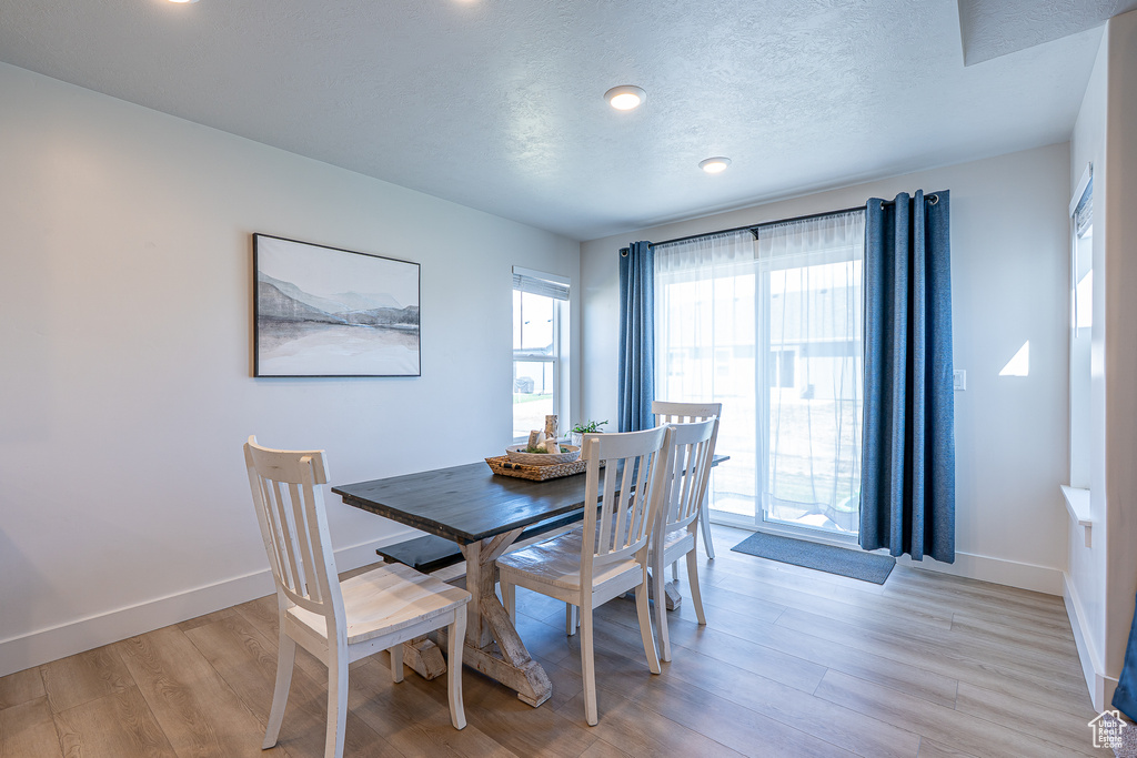 Dining space with light wood-style floors, baseboards, and a textured ceiling