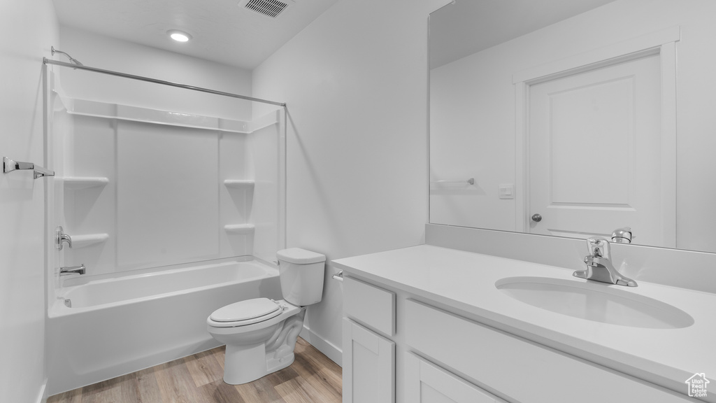 Bathroom featuring wood finished floors, toilet, vanity, shower / washtub combination, and baseboards