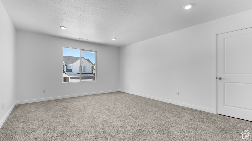 Carpeted spare room featuring baseboards, recessed lighting, and a textured ceiling