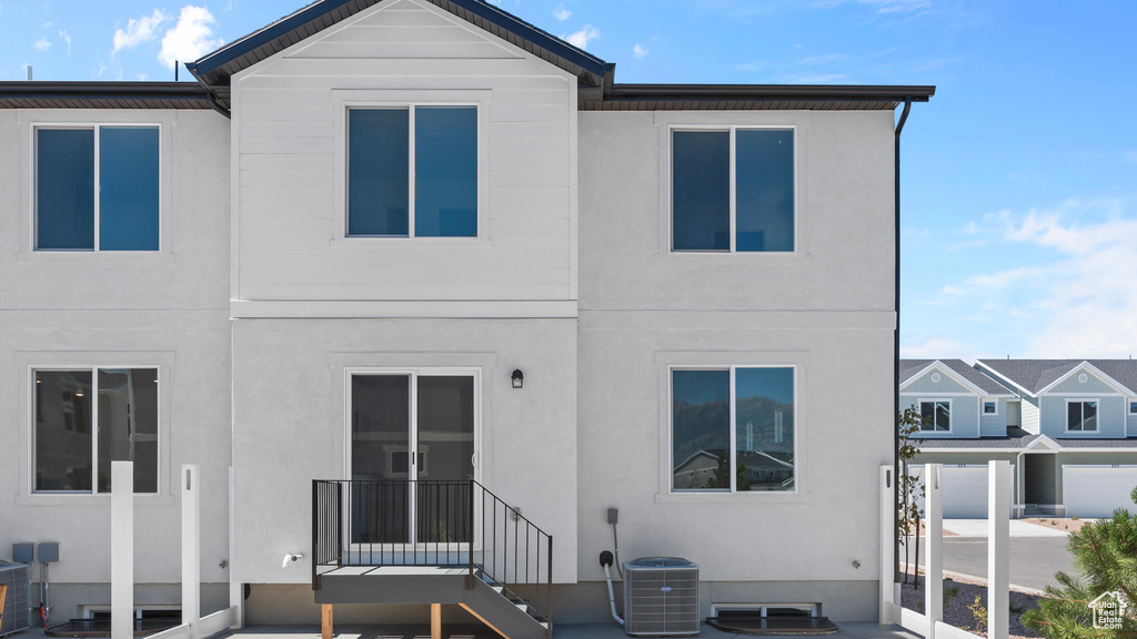 Back of property featuring stucco siding and central AC
