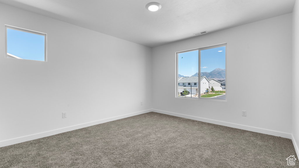Carpeted empty room featuring plenty of natural light and baseboards