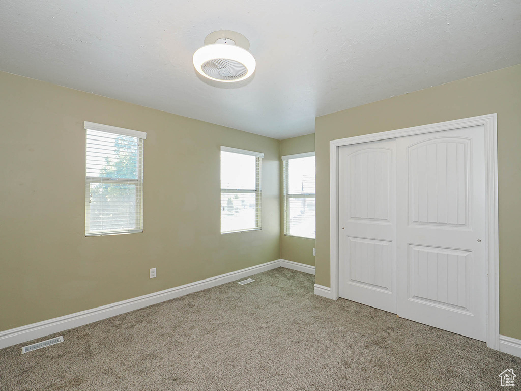 Unfurnished bedroom with carpet floors, baseboards, and a closet