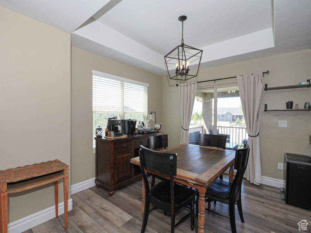 Dining room with a chandelier, baseboards, light wood-style floors, and a tray ceiling