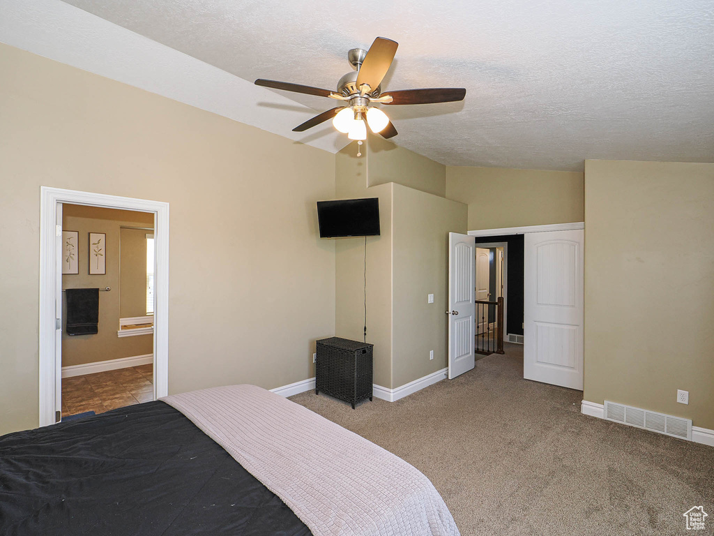 Bedroom featuring vaulted ceiling, a textured ceiling, carpet floors, baseboards, and a ceiling fan