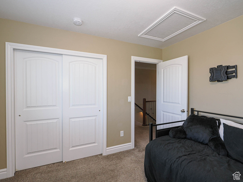 Carpeted bedroom with attic access, a closet, and baseboards