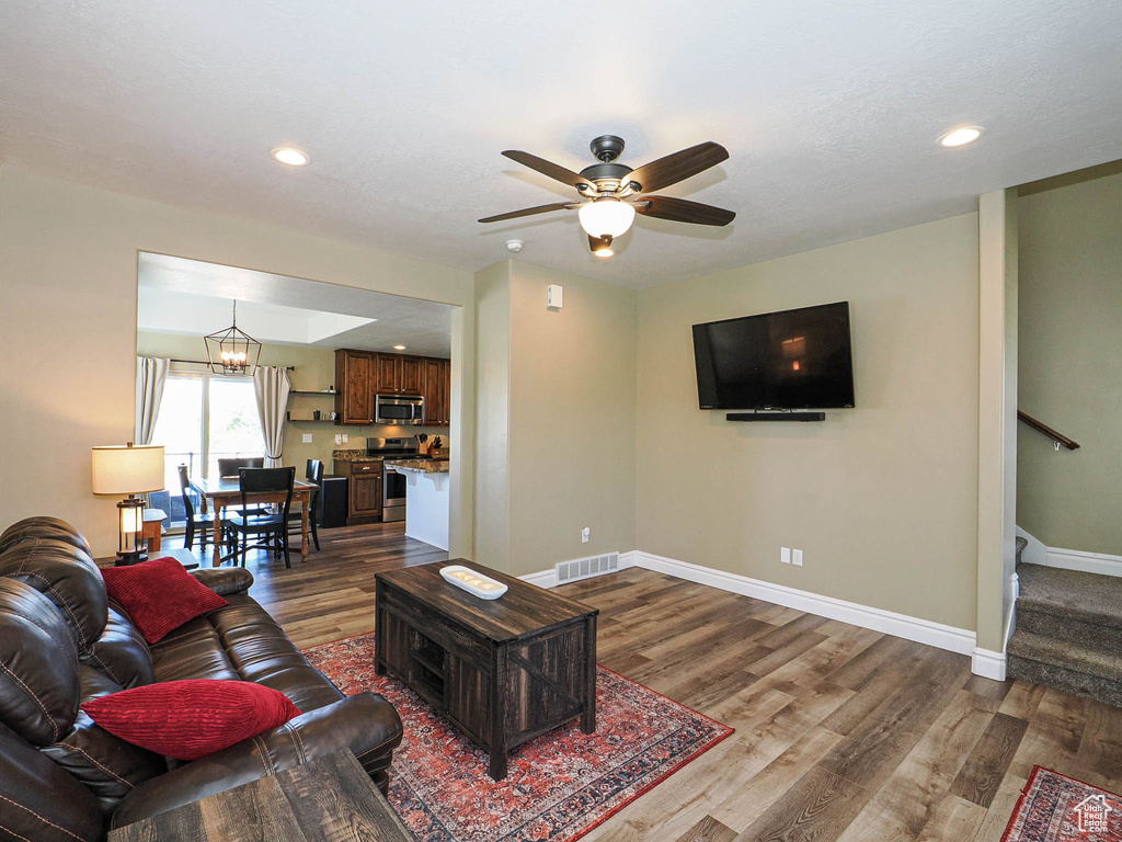 Living area featuring dark wood-type flooring, baseboards, stairs, recessed lighting, and ceiling fan