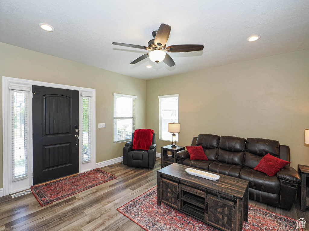 Living room with wood finished floors, baseboards, ceiling fan, and recessed lighting