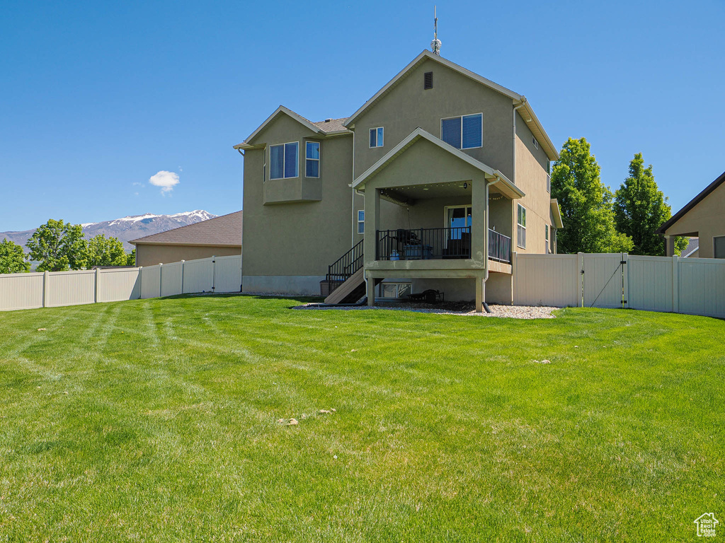 Back of house featuring a gate, stairway, stucco siding, and a mountain view