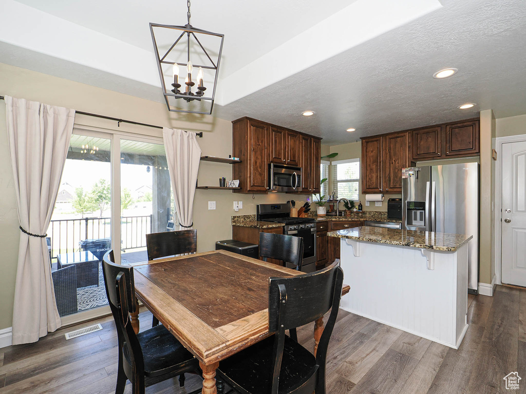 Dining area with a chandelier, dark wood-type flooring, and recessed lighting
