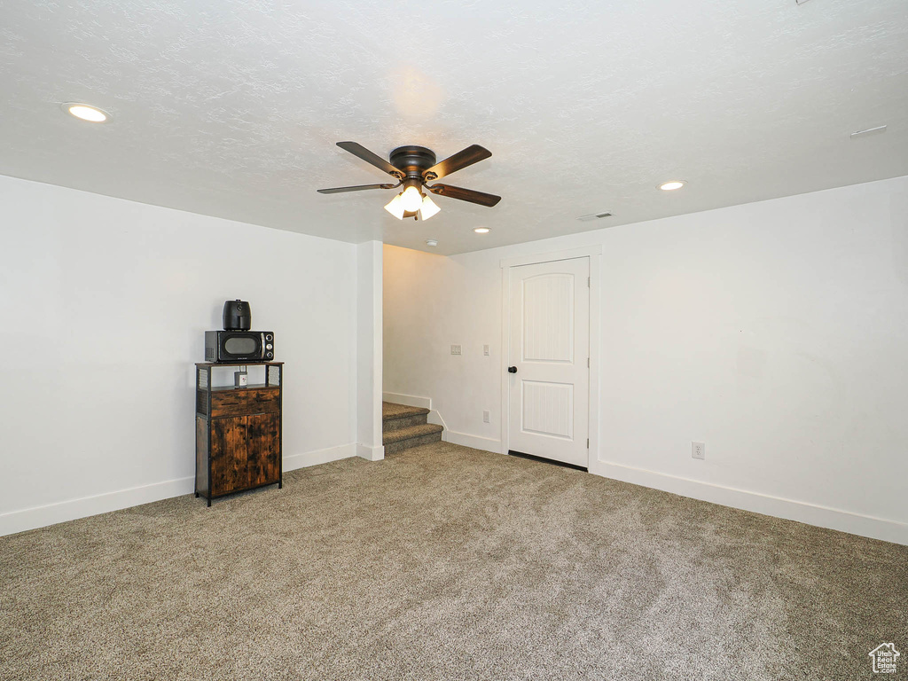Carpeted spare room featuring a ceiling fan, recessed lighting, baseboards, and stairs