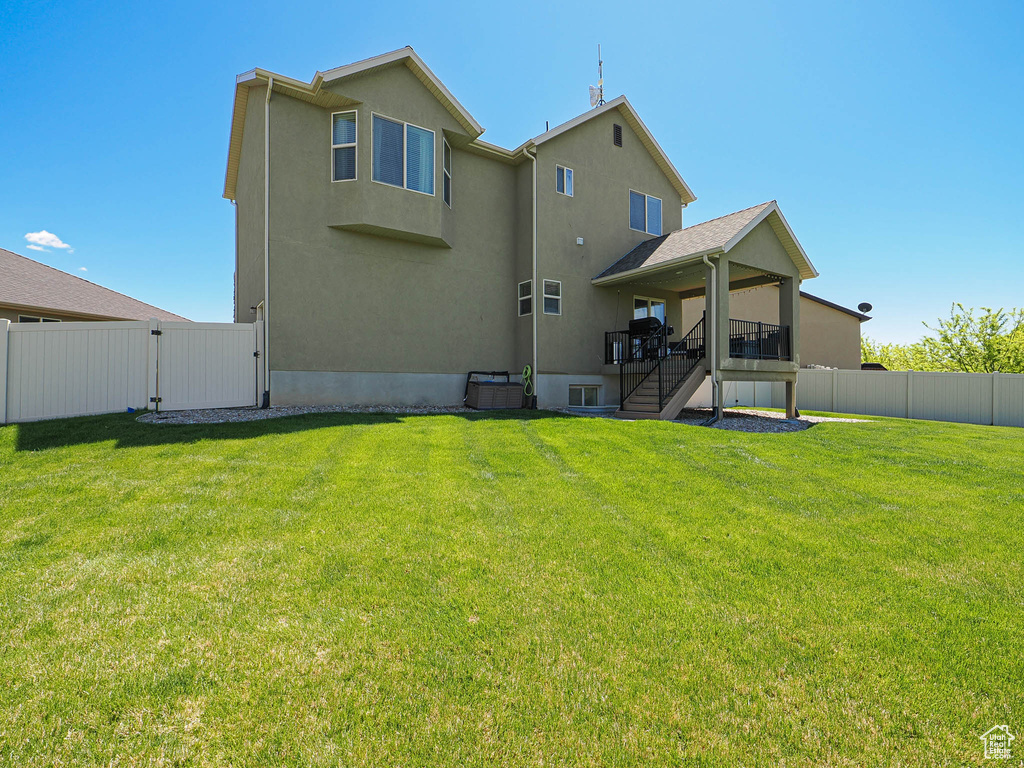 Back of house featuring stairway, a gate, stucco siding, and a deck